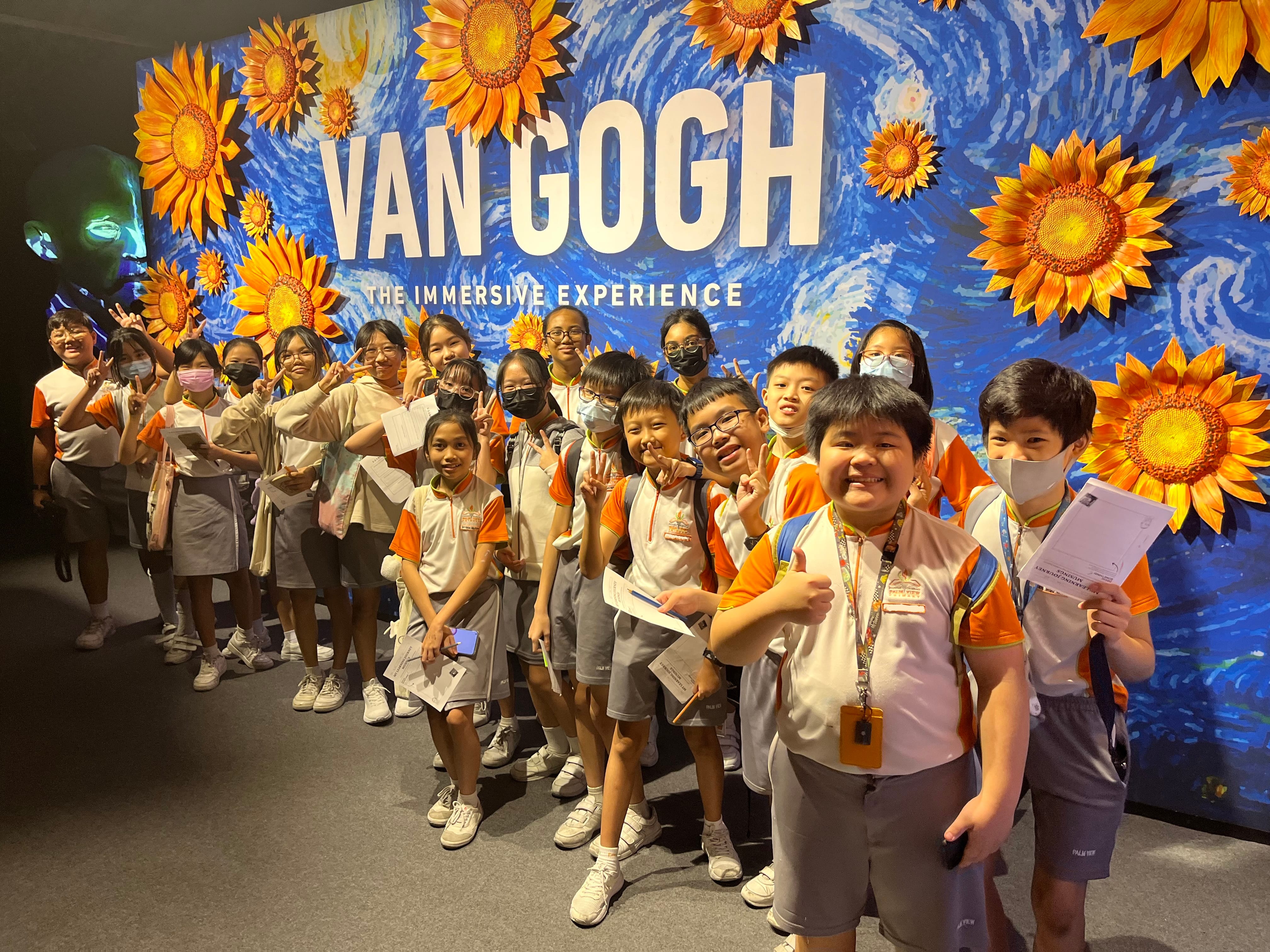 Students smiling in front of the Van Gogh Immersive Experience sign